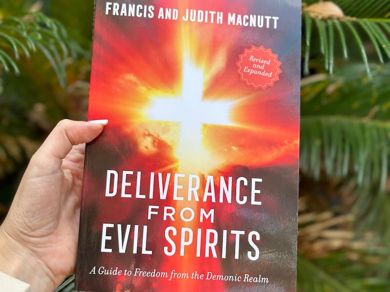 A hand holding the book Deliverance From Evil Spirts by Francis & Judith MacNutt