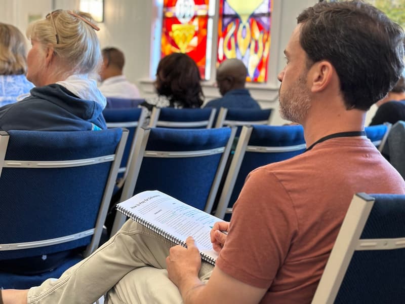 Man sitting taking notes in a School of Healing Prayer class.