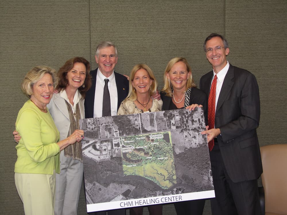 A group holding up an enlarged photo of the CHM Healing Center land.