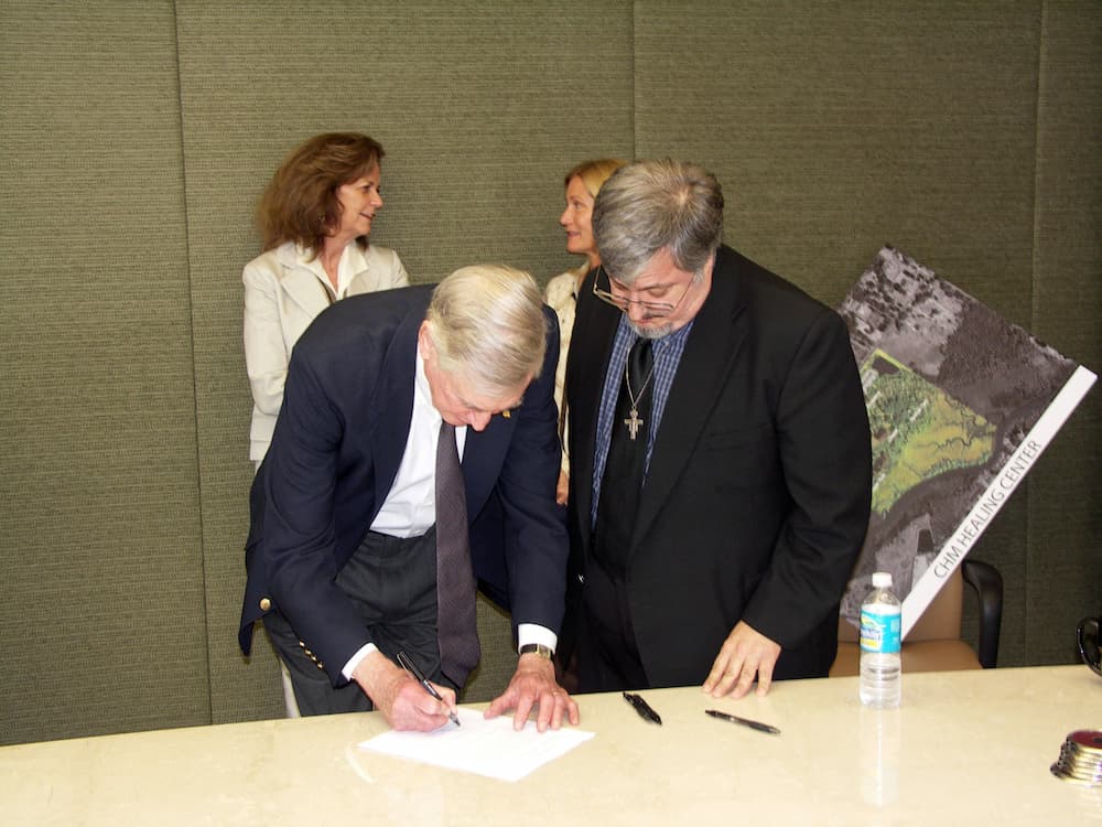 Francis signing a form for the Healing Place land.