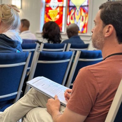 Man sitting taking notes in a School of Healing Prayer class.
